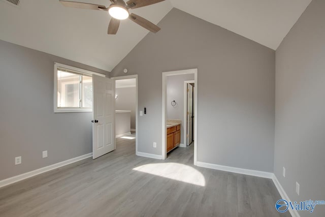 unfurnished bedroom with light wood finished floors, visible vents, ensuite bathroom, high vaulted ceiling, and baseboards