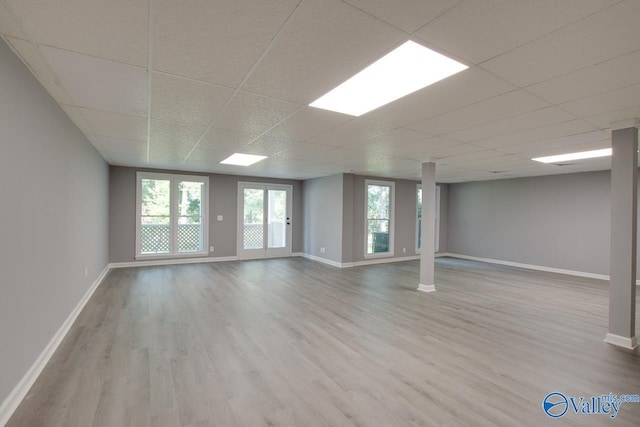 unfurnished room featuring light wood finished floors, baseboards, and a drop ceiling