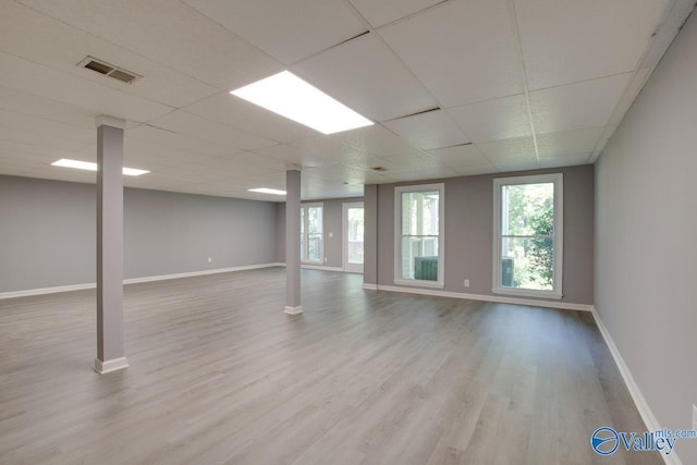 spare room with light wood-type flooring, a healthy amount of sunlight, visible vents, and a drop ceiling