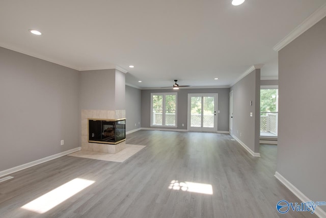 unfurnished living room with recessed lighting, light wood-style floors, baseboards, a tiled fireplace, and crown molding