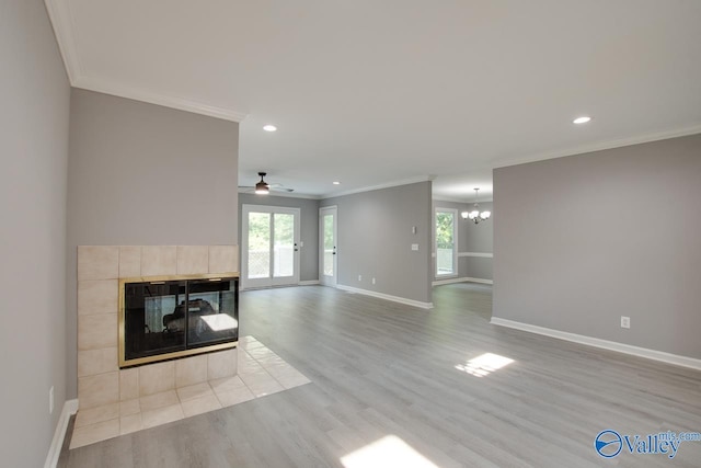 unfurnished living room with light wood-type flooring, a tiled fireplace, a wealth of natural light, and baseboards