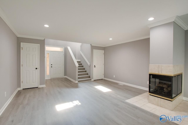 unfurnished living room with light wood-type flooring, a fireplace, baseboards, and stairs
