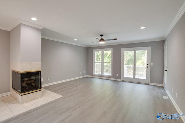 unfurnished living room with ornamental molding, light wood-type flooring, baseboards, and a tiled fireplace