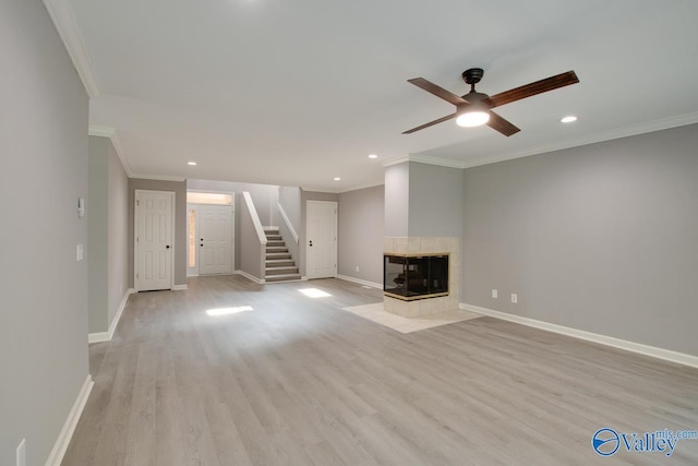 unfurnished living room with baseboards, stairs, crown molding, light wood-style floors, and a fireplace