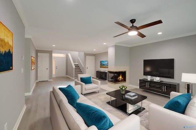 living room featuring stairs, crown molding, light wood-type flooring, a multi sided fireplace, and recessed lighting