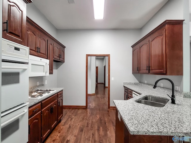 kitchen featuring sink, light stone counters, dark brown cabinets, dark hardwood / wood-style floors, and white appliances