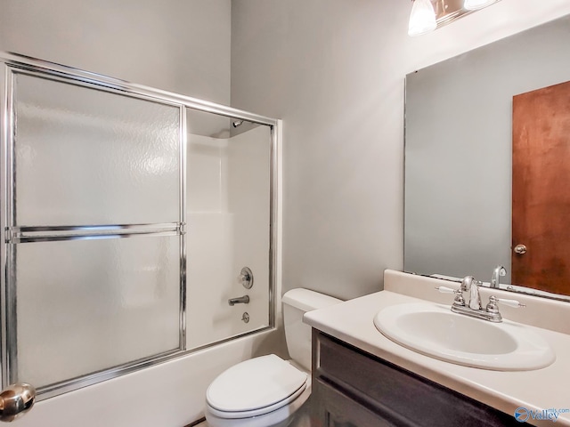 full bathroom with enclosed tub / shower combo, vanity, and toilet