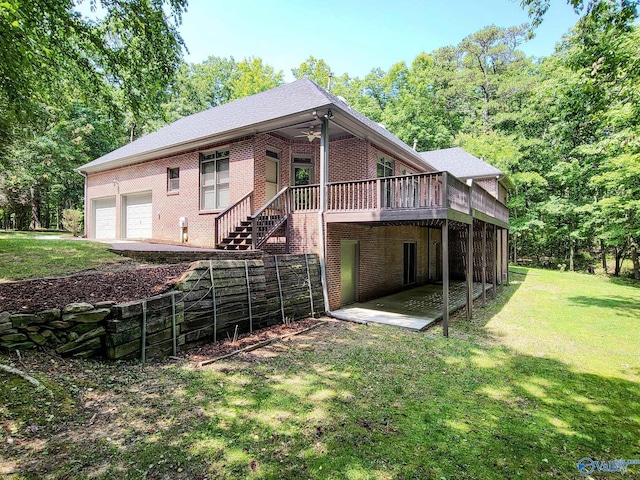 back of property with ceiling fan, a garage, and a lawn