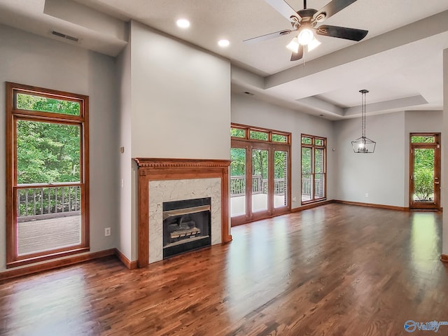 unfurnished living room featuring a tray ceiling, dark wood-type flooring, and plenty of natural light