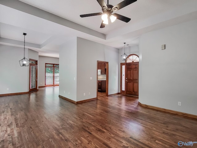 interior space featuring dark hardwood / wood-style floors, ceiling fan with notable chandelier, and a raised ceiling