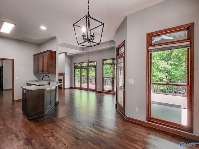 kitchen with pendant lighting, dark wood-type flooring, light stone countertops, and sink