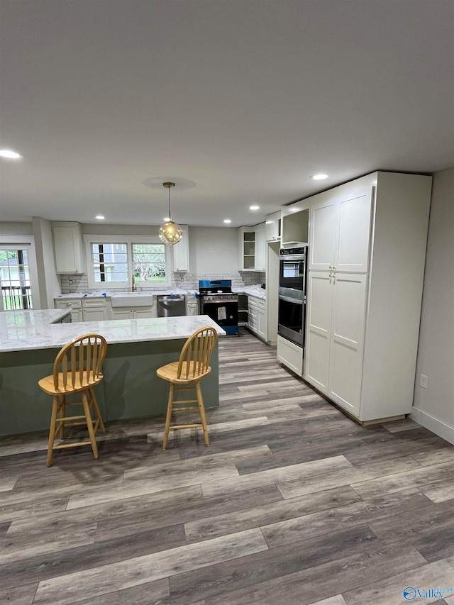 kitchen with white cabinets, decorative light fixtures, stainless steel appliances, and a healthy amount of sunlight