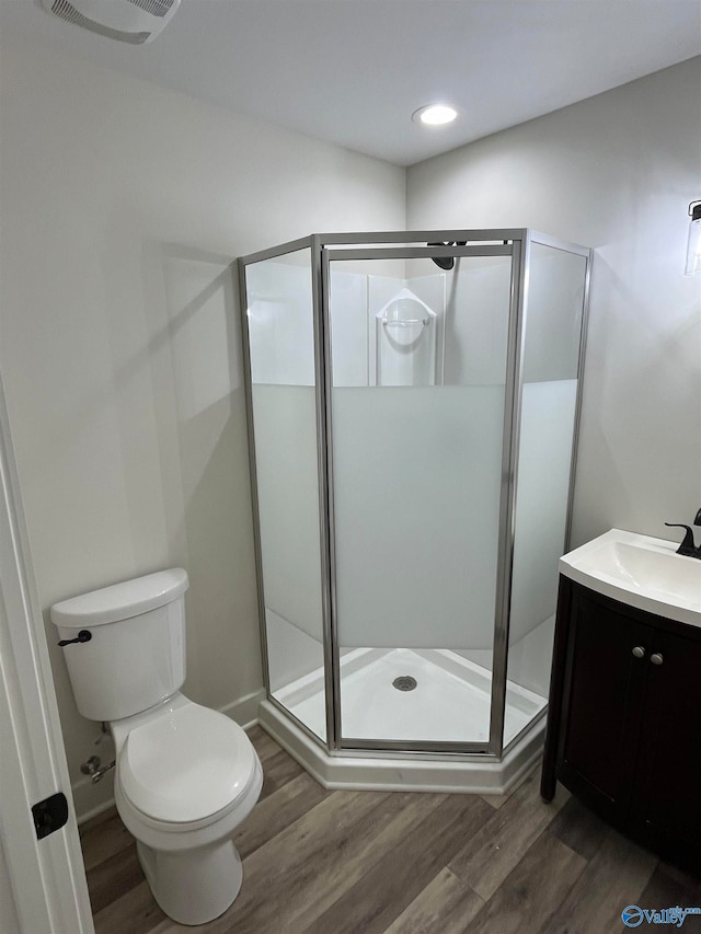 bathroom featuring walk in shower, hardwood / wood-style floors, vanity, and toilet