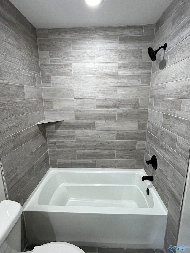 bathroom featuring tiled shower / bath combo and toilet