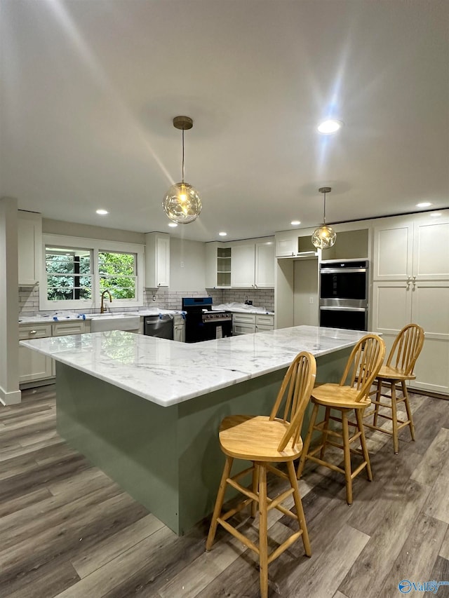 kitchen featuring light stone counters, pendant lighting, stainless steel appliances, and white cabinets