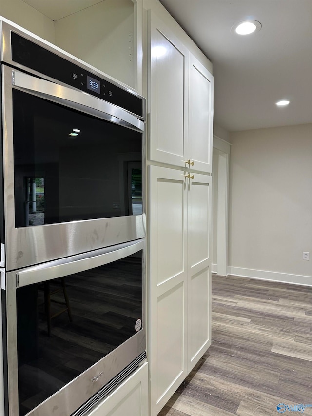 interior space featuring white cabinets, double oven, and light wood-type flooring