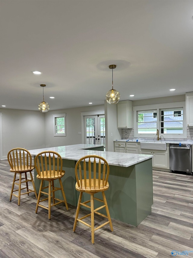 kitchen featuring dishwasher, light stone countertops, plenty of natural light, and hanging light fixtures