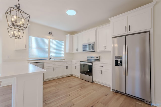 kitchen featuring light countertops, appliances with stainless steel finishes, light wood-style floors, white cabinetry, and a peninsula