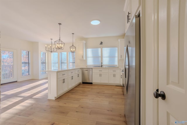 kitchen with stainless steel appliances, light wood-type flooring, plenty of natural light, and a peninsula