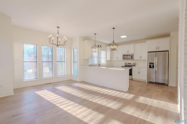 kitchen featuring light wood-style flooring, a sink, light countertops, appliances with stainless steel finishes, and an inviting chandelier