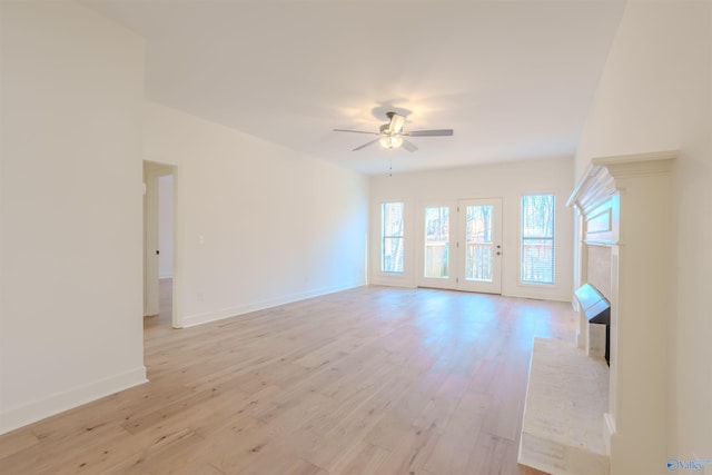 unfurnished living room with light wood-style floors, a fireplace, baseboards, and ceiling fan