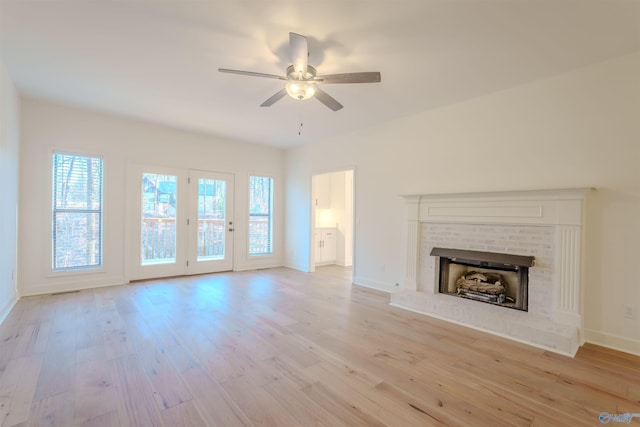 unfurnished living room with ceiling fan, a fireplace, light wood-style flooring, and baseboards