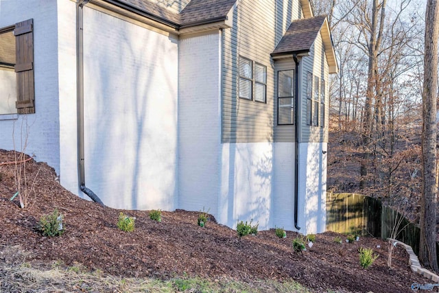 view of property exterior featuring a shingled roof and brick siding