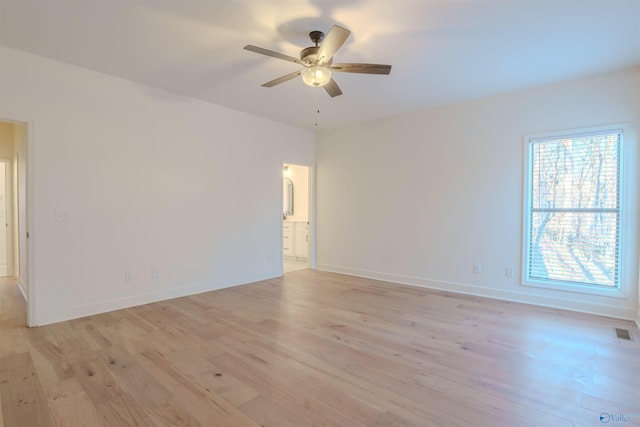 spare room featuring baseboards, light wood-type flooring, a wealth of natural light, and a ceiling fan