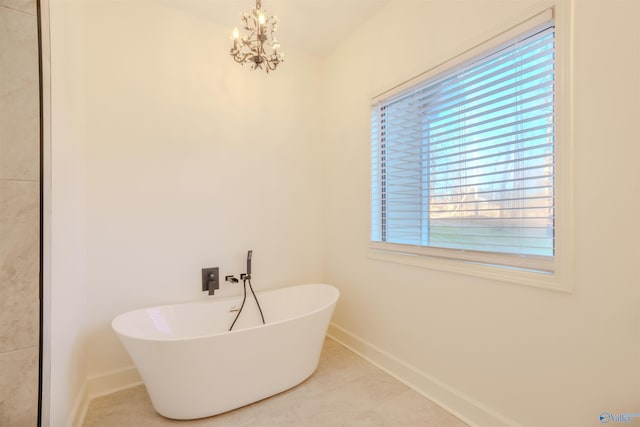 full bathroom with a soaking tub, an inviting chandelier, and baseboards