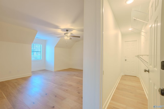 additional living space with light wood-type flooring, vaulted ceiling, baseboards, and ceiling fan