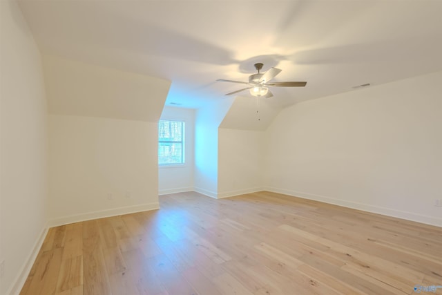 additional living space with light wood-type flooring, baseboards, vaulted ceiling, and a ceiling fan