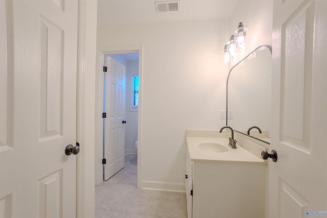 bathroom featuring baseboards, visible vents, vanity, and toilet