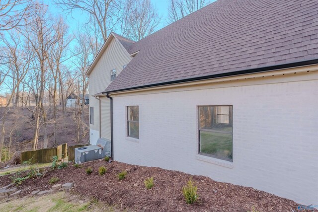 view of side of home with a shingled roof and brick siding