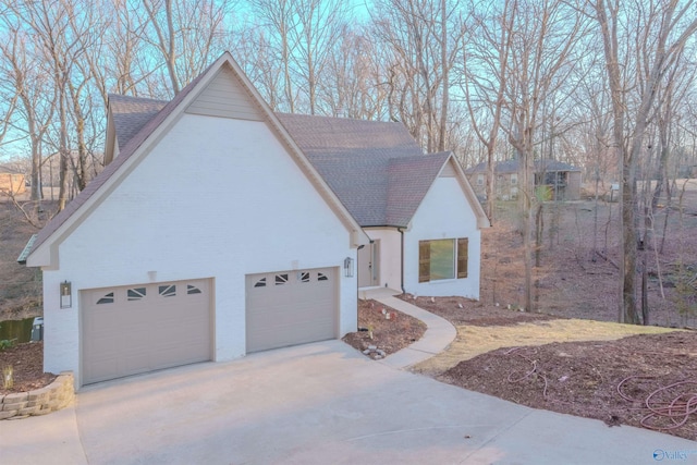 exterior space featuring driveway, a shingled roof, and a garage