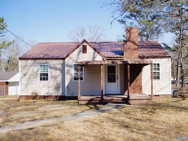 rear view of house featuring a porch, a yard, a chimney, crawl space, and metal roof