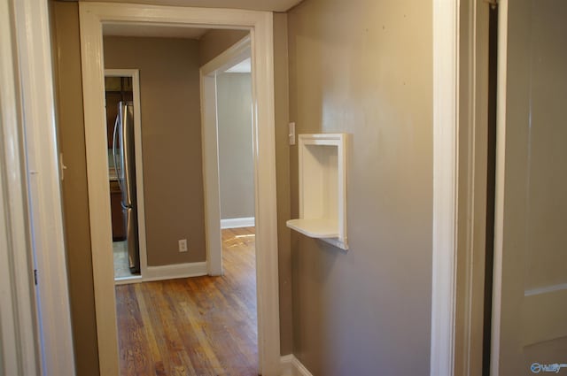 corridor with wood finished floors and baseboards