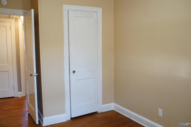 unfurnished bedroom featuring dark wood-type flooring and baseboards
