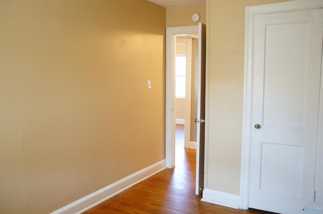 corridor with dark wood finished floors and baseboards