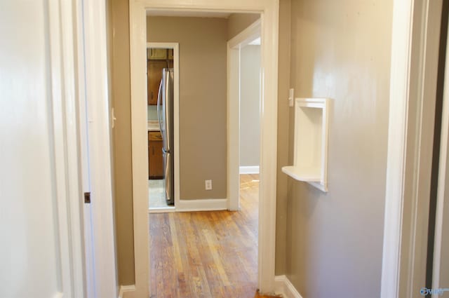 hall with baseboards and light wood-style floors