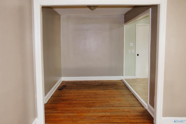 hallway featuring baseboards and wood finished floors