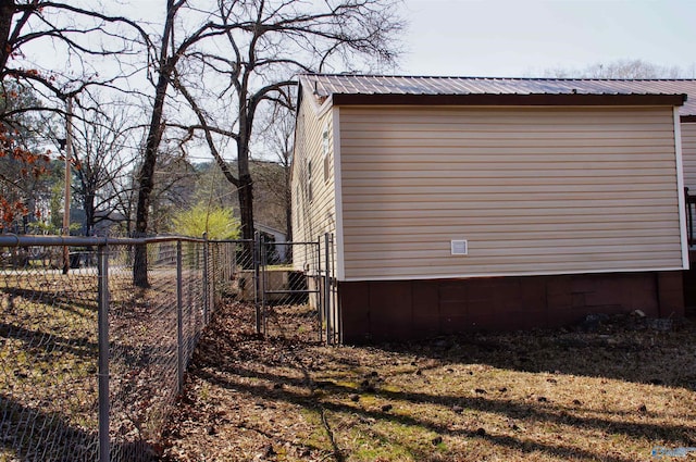 view of side of property with a gate, metal roof, and fence