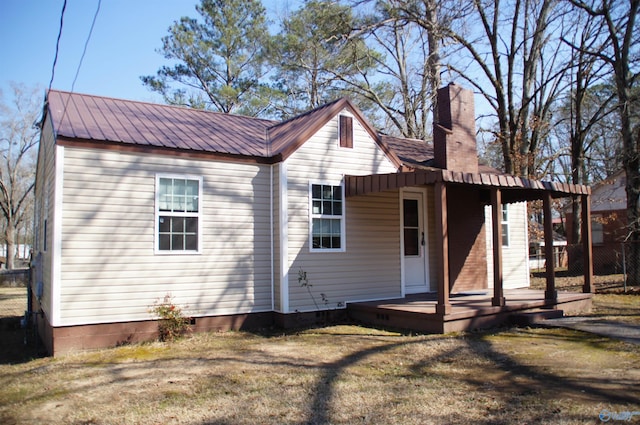 back of property featuring crawl space, a chimney, a yard, and metal roof