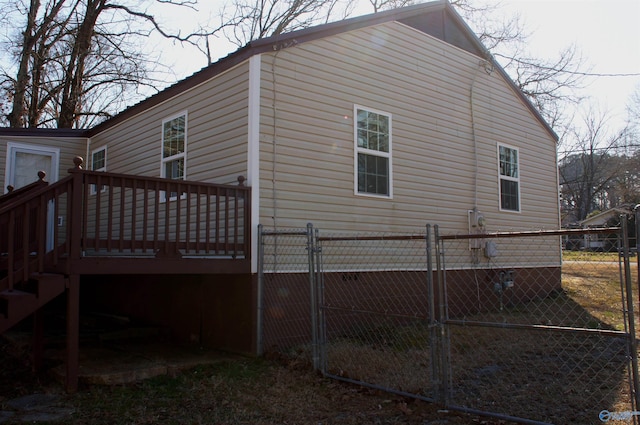 view of home's exterior featuring crawl space, a wooden deck, fence, and a gate