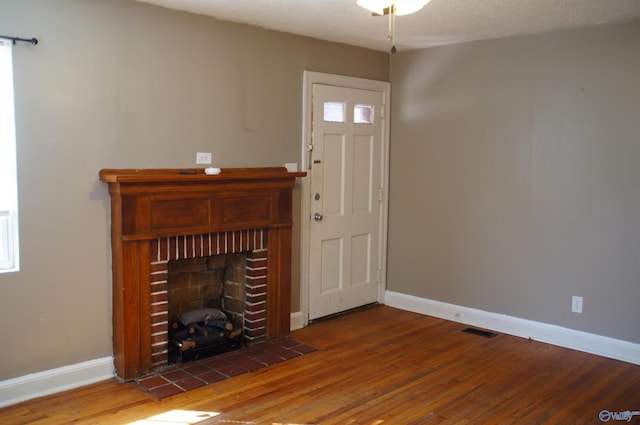 unfurnished living room featuring visible vents, baseboards, and wood finished floors