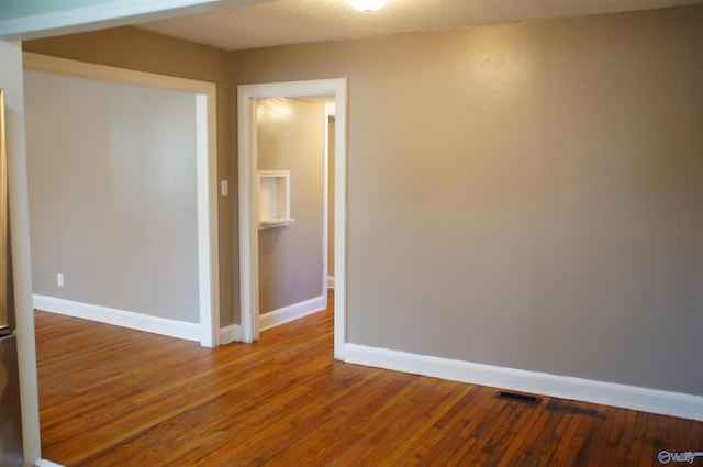 unfurnished room featuring hardwood / wood-style floors, visible vents, and baseboards