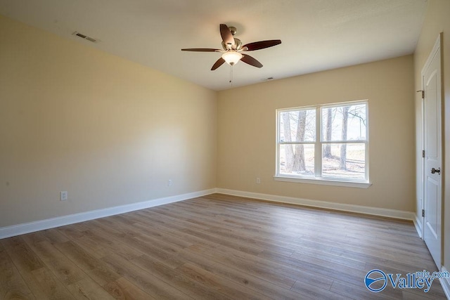spare room with a ceiling fan, baseboards, visible vents, and wood finished floors