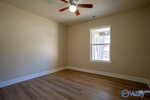 unfurnished room with visible vents, ceiling fan, baseboards, and wood finished floors