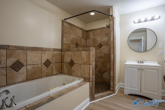 bathroom featuring a jetted tub, vanity, wood finished floors, and tiled shower