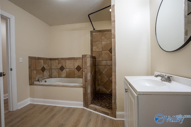full bath featuring wood finished floors, vanity, baseboards, a tile shower, and a bath