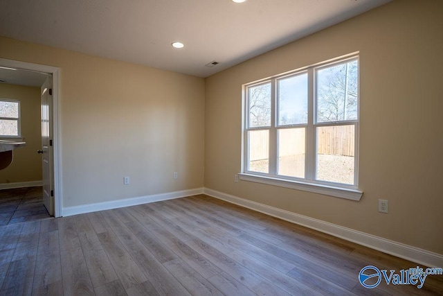 unfurnished room featuring visible vents, baseboards, and wood finished floors